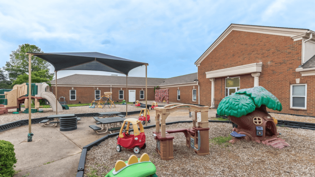 Outdoor playground with playhouse, slide, and sandbox for children.
